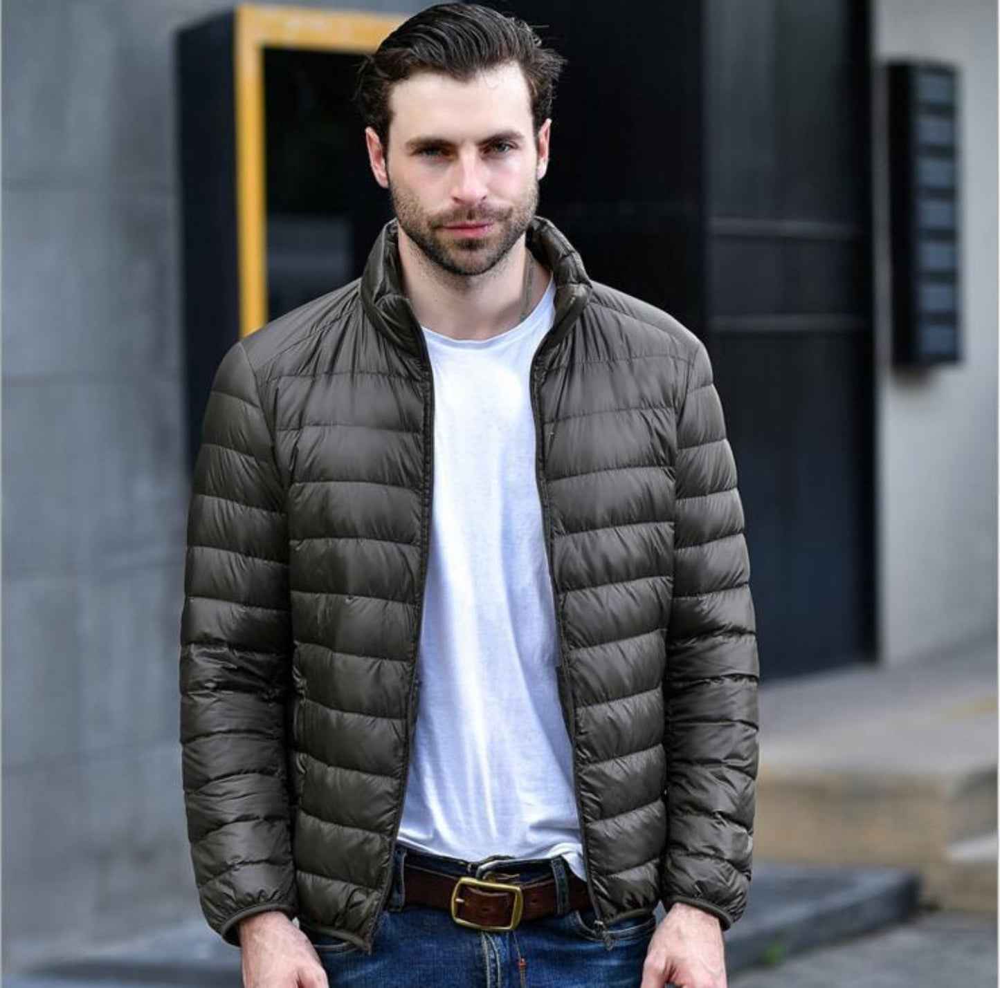 A model wearing a lightweight brown puffer jacket paired with a casual outfit outdoors.