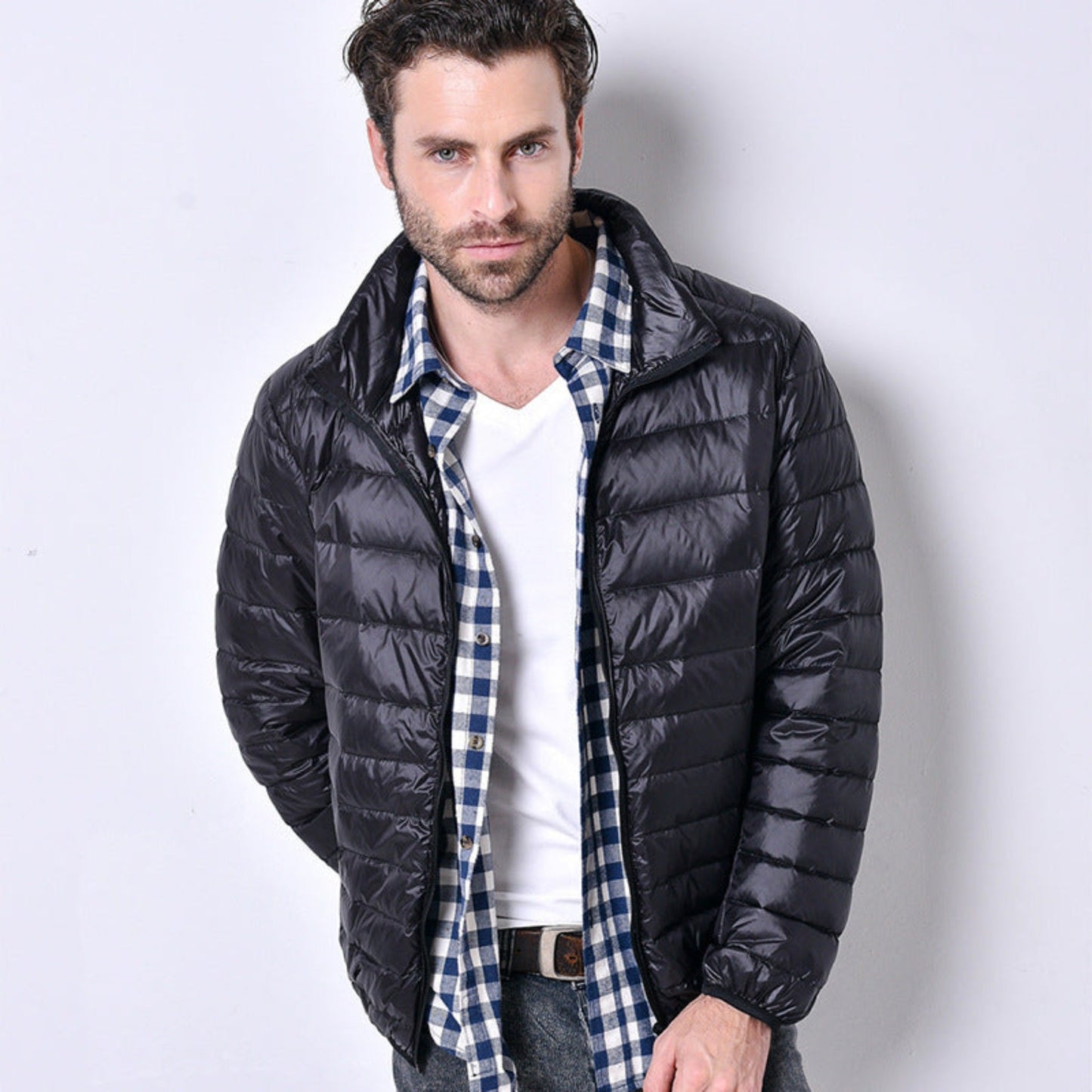 A model showcasing a black lightweight puffer jacket styled with a checkered shirt.