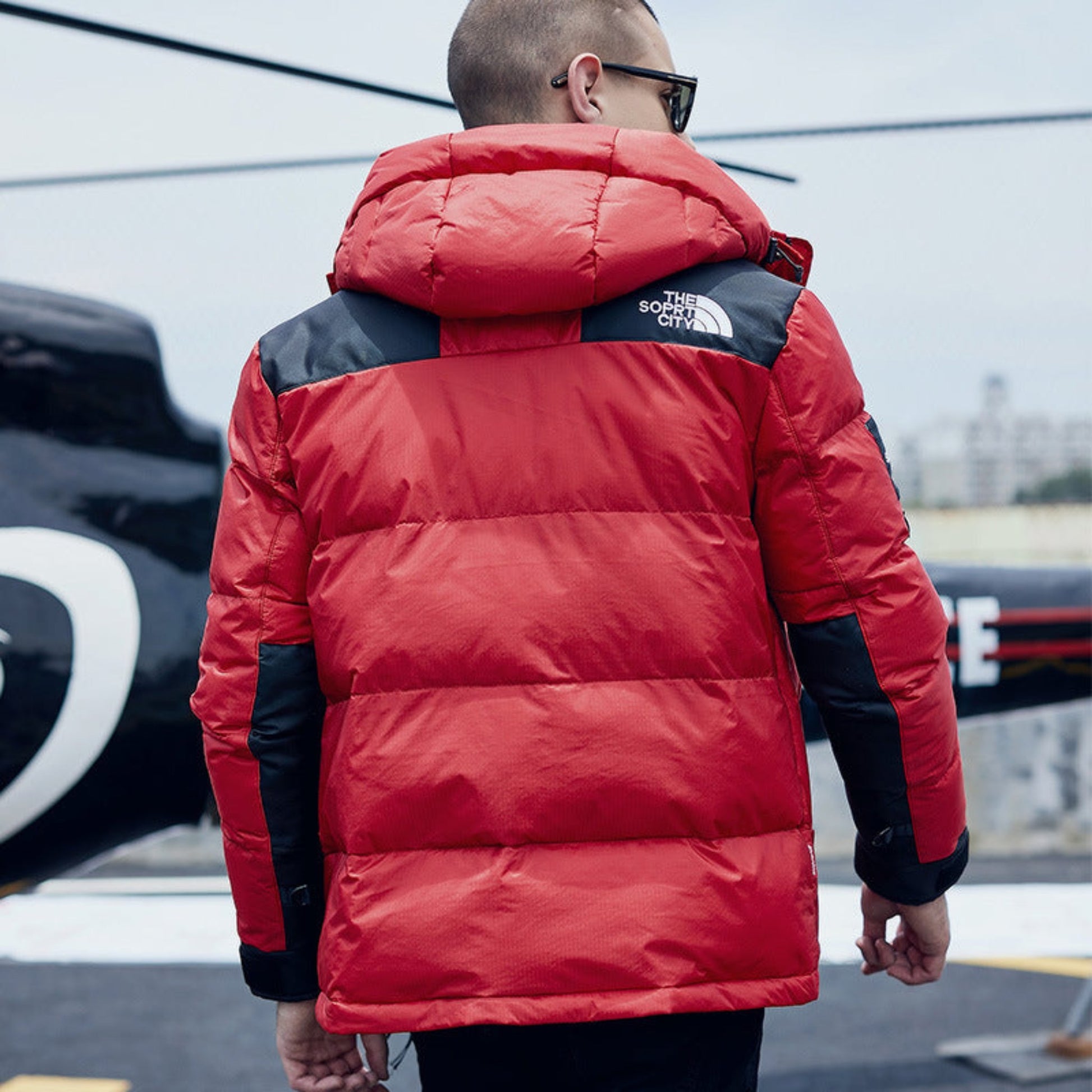 Back view of a man showcasing the detachable hood and quilted design of a red jacket.