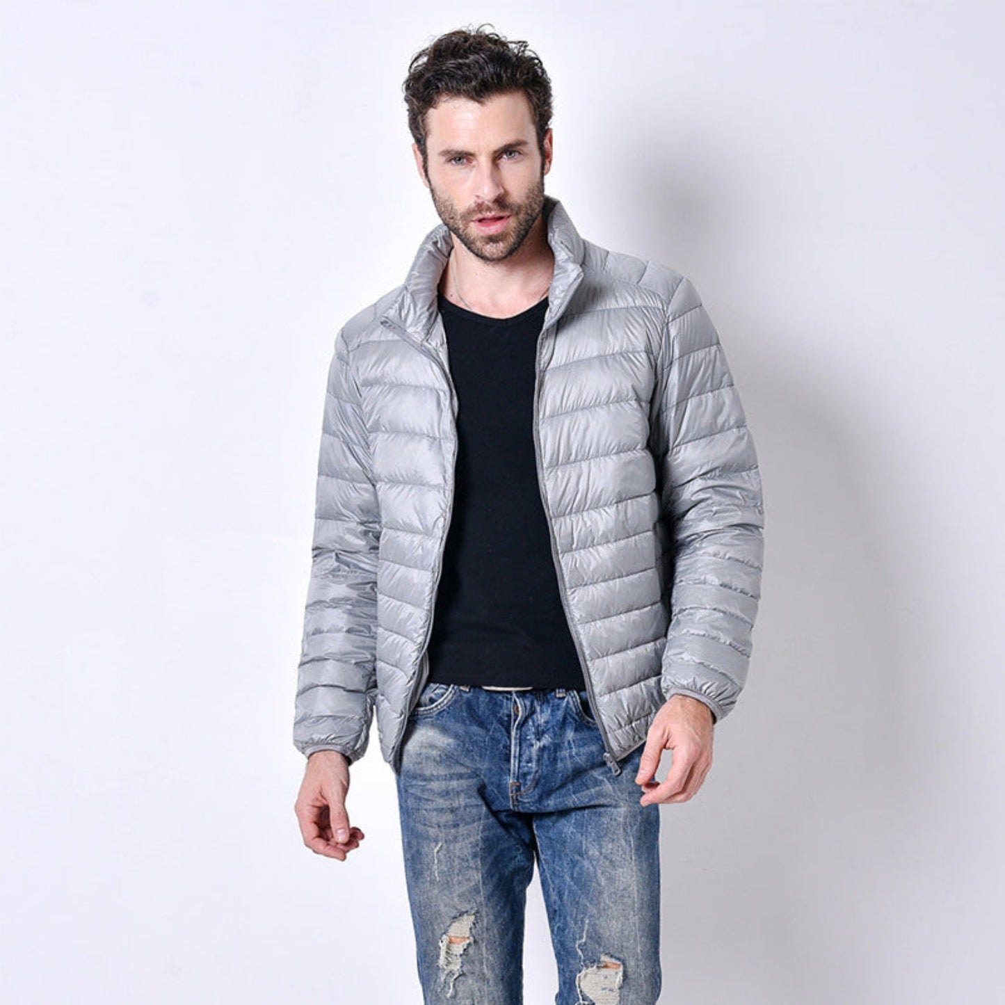 A model wearing a lightweight gray puffer jacket paired with jeans in a casual pose.