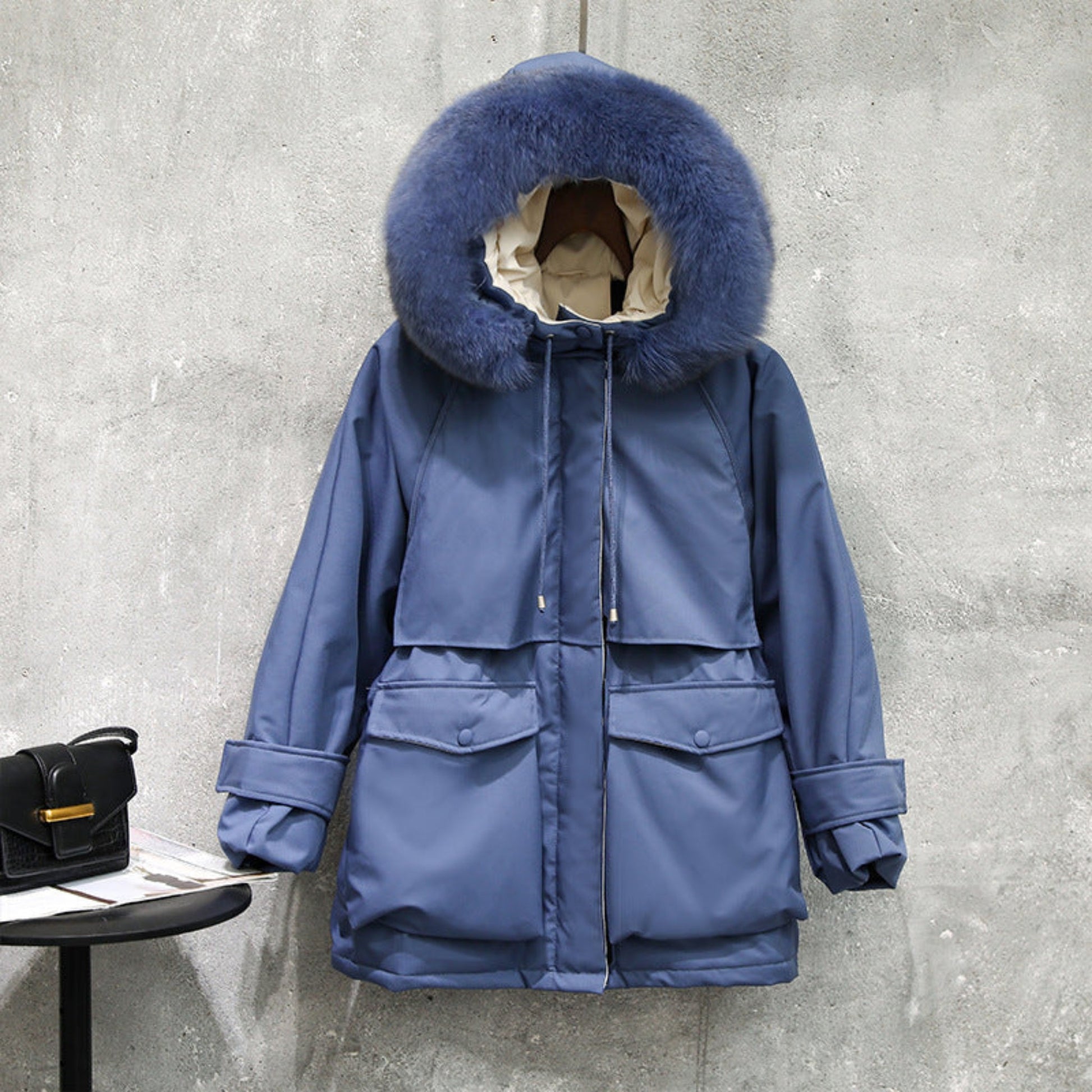 Front view of a women’s blue fur-collar winter jacket, displayed on a mannequin, with functional zippers and cozy design.