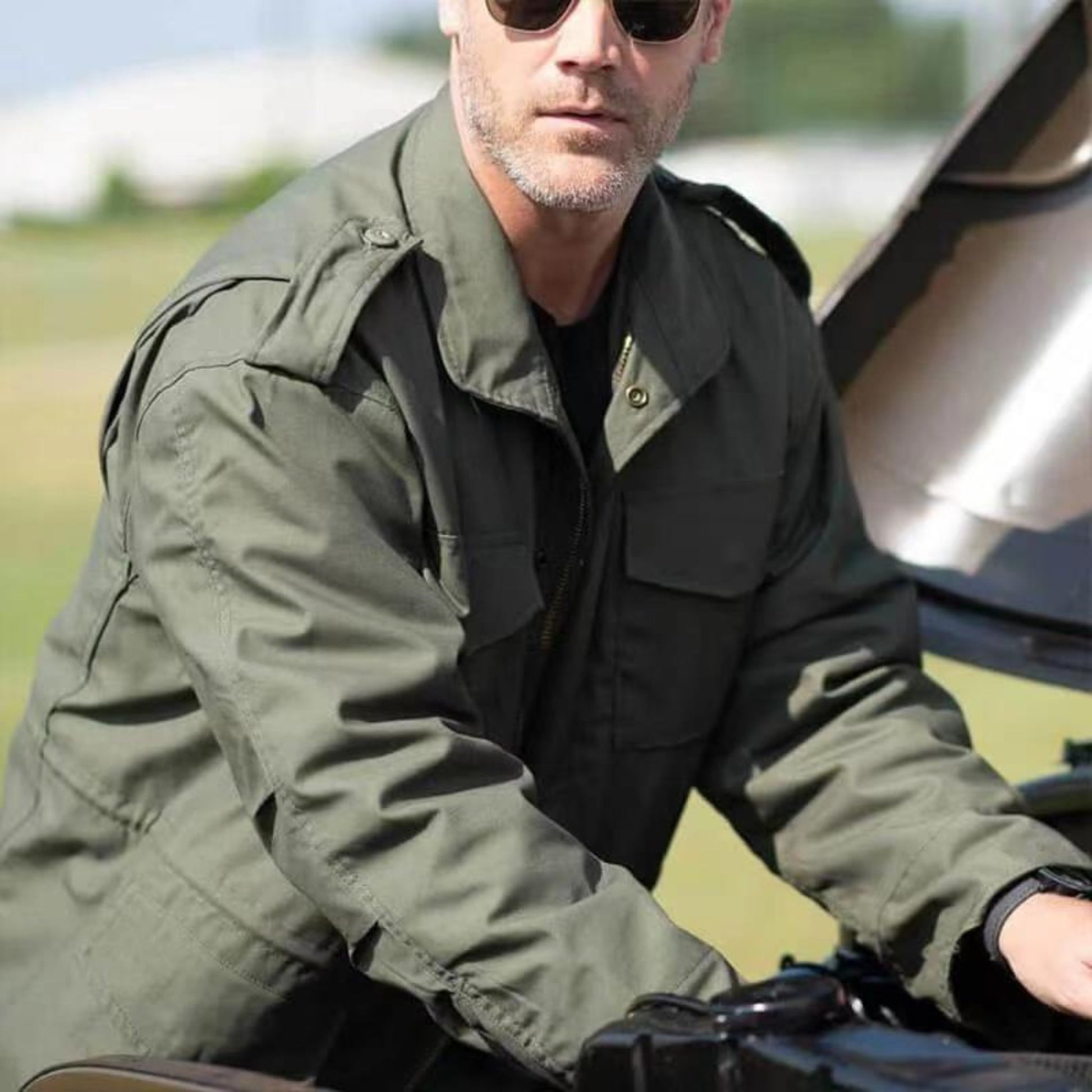 Model inspecting a vintage car while wearing a military-inspired green jacket.