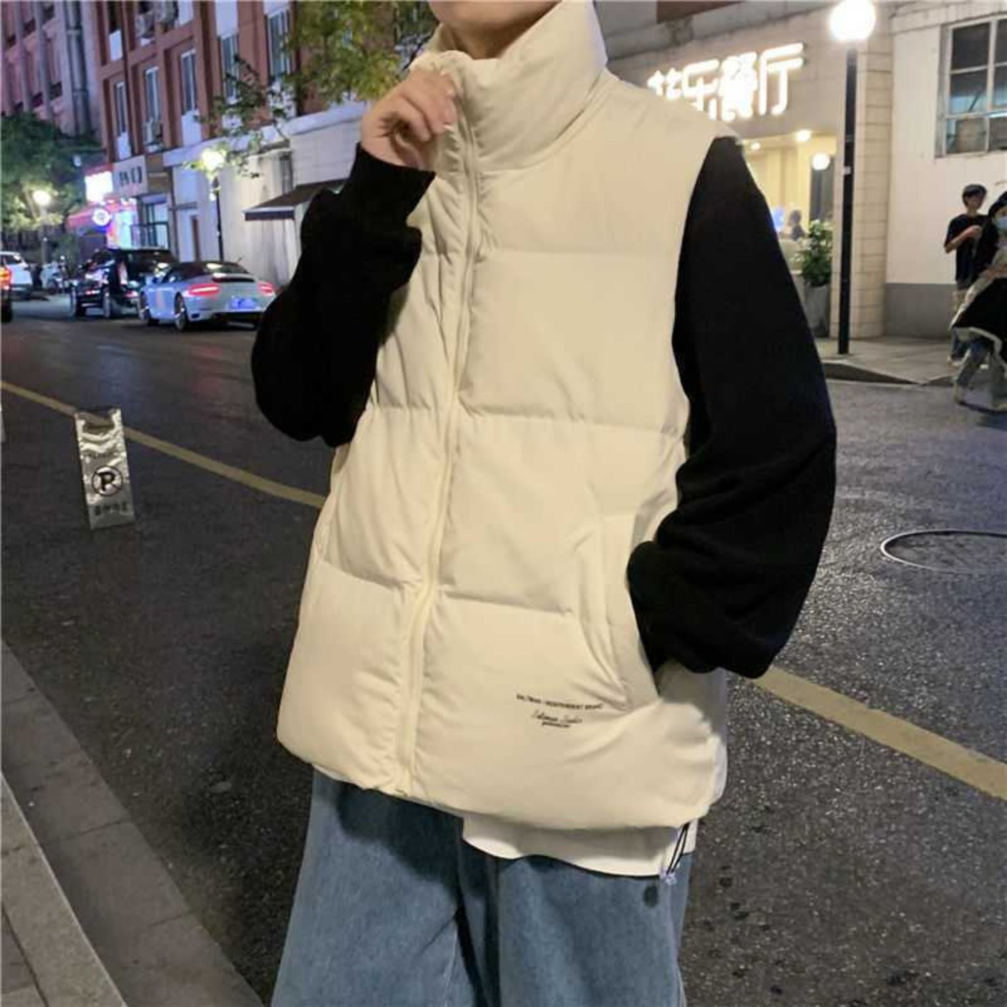 Model in khaki cotton sleeveless vest paired with a black hoodie outdoors.